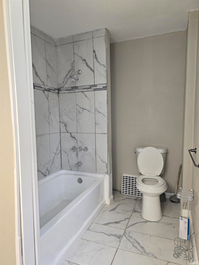 bathroom featuring tiled shower / bath combo and toilet