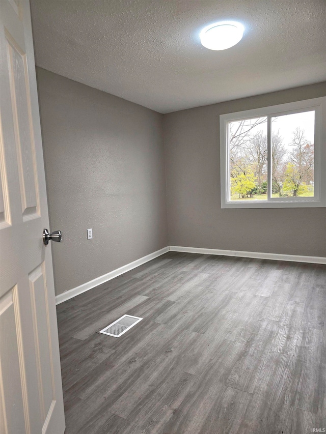 empty room featuring dark hardwood / wood-style flooring and a textured ceiling