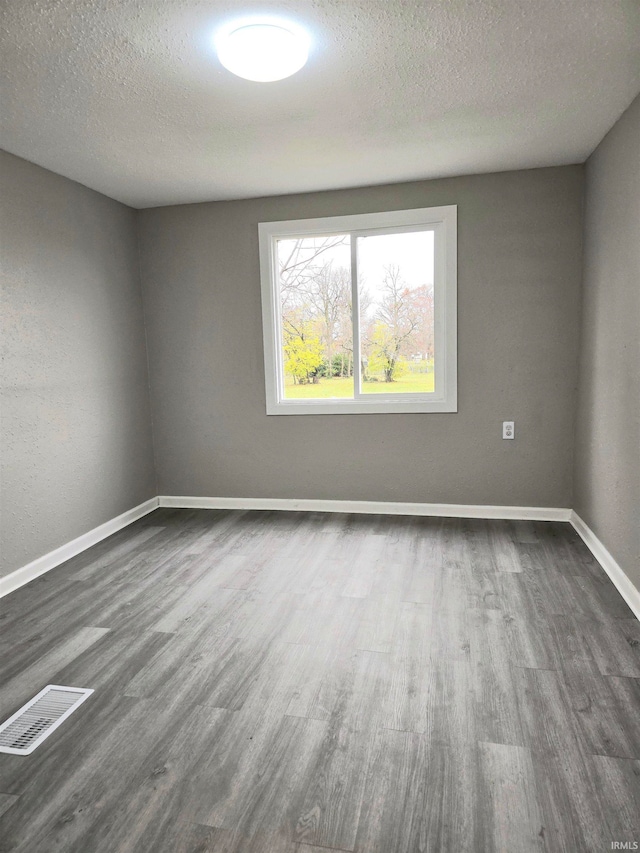 unfurnished room with dark hardwood / wood-style flooring and a textured ceiling