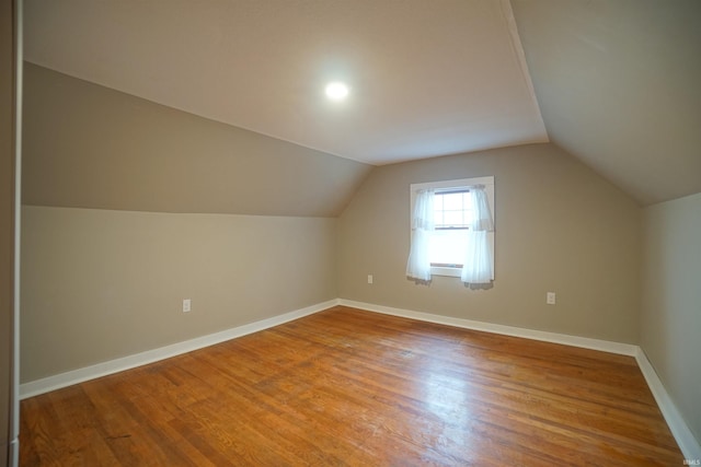 additional living space featuring vaulted ceiling and hardwood / wood-style flooring