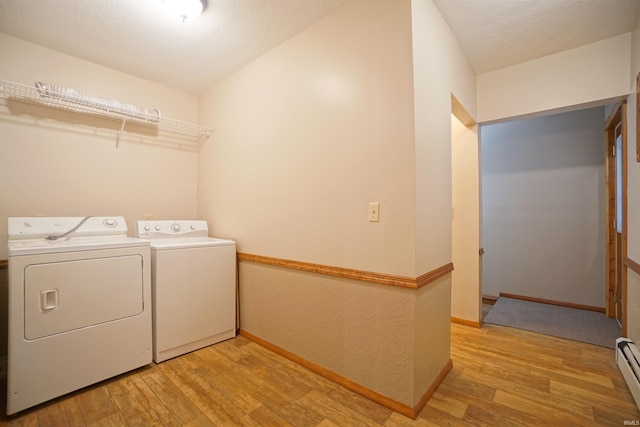 laundry room with washing machine and dryer, light hardwood / wood-style floors, a textured ceiling, and a baseboard heating unit