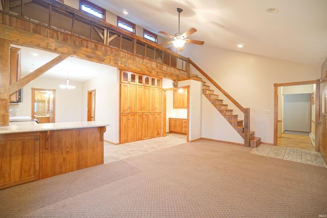 unfurnished living room with ceiling fan with notable chandelier, light colored carpet, and high vaulted ceiling