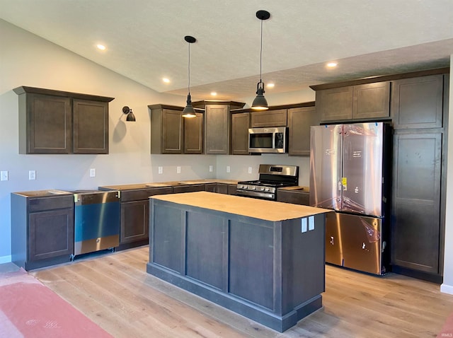 kitchen with light wood-type flooring, hanging light fixtures, vaulted ceiling, and appliances with stainless steel finishes