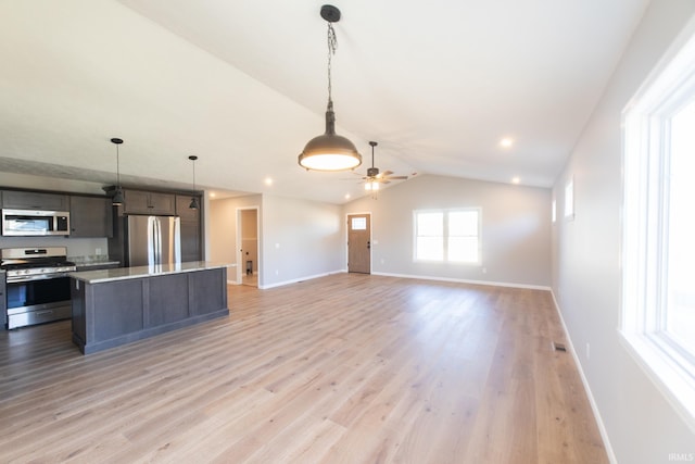 kitchen featuring appliances with stainless steel finishes, vaulted ceiling, ceiling fan, light hardwood / wood-style flooring, and a kitchen island