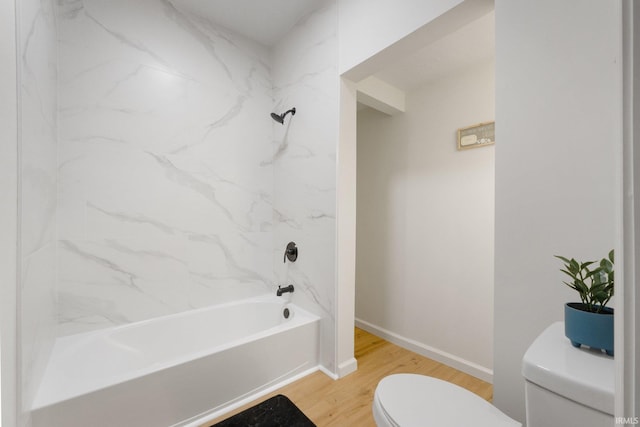 bathroom featuring hardwood / wood-style floors, washtub / shower combination, and toilet