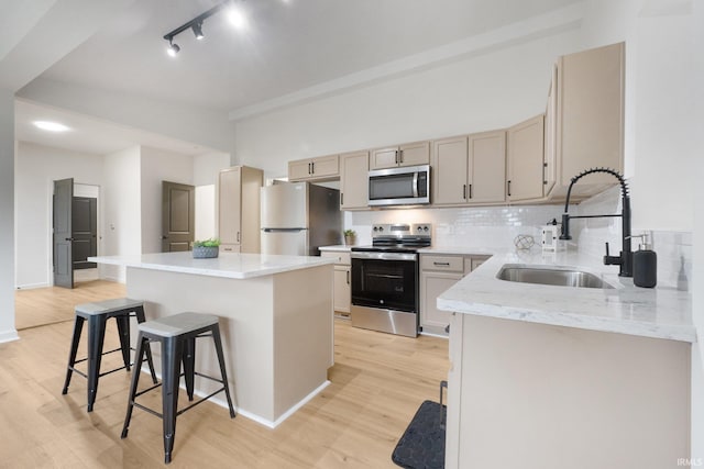 kitchen with a center island, a kitchen breakfast bar, sink, light wood-type flooring, and appliances with stainless steel finishes