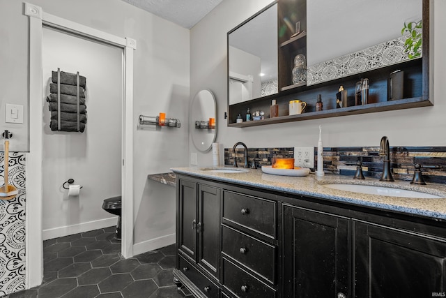 bathroom featuring double vanity, a sink, toilet, and tile patterned floors