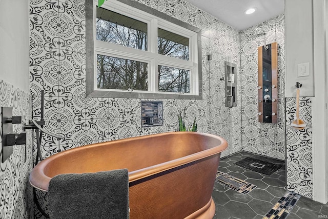 full bathroom featuring a freestanding tub, tile patterned flooring, and tile walls