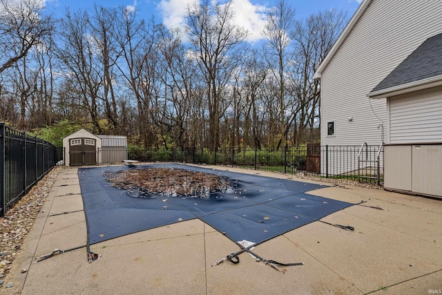 view of pool featuring a patio area, fence, a shed, an outdoor structure, and a diving board