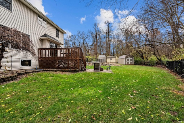 view of yard featuring an outbuilding, a storage unit, a fenced backyard, and a wooden deck