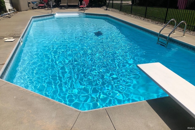 view of pool featuring fence, a diving board, and a fenced in pool