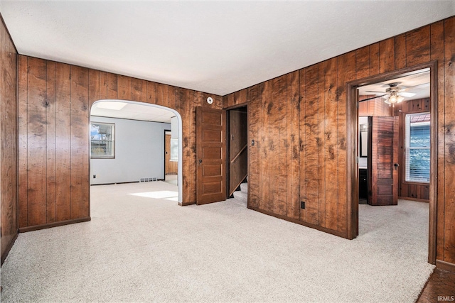 carpeted empty room with wooden walls and ceiling fan