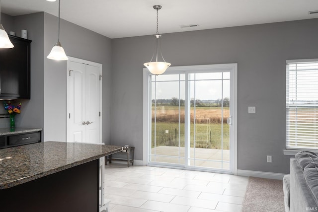 kitchen with decorative light fixtures, dark stone countertops, and light tile patterned floors