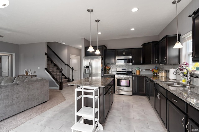 kitchen featuring appliances with stainless steel finishes, a kitchen island, pendant lighting, and dark stone countertops