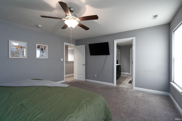 bedroom featuring ceiling fan, light carpet, and ensuite bath