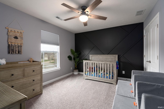 bedroom with carpet floors, a nursery area, and ceiling fan