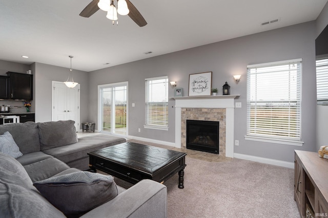 living room with light carpet, a fireplace, and ceiling fan