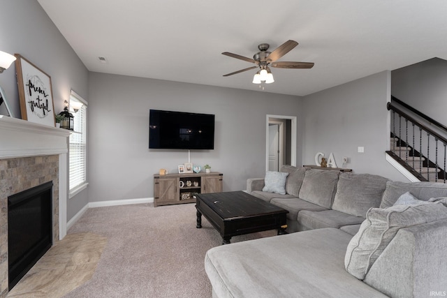 living room featuring ceiling fan, light colored carpet, and a tile fireplace