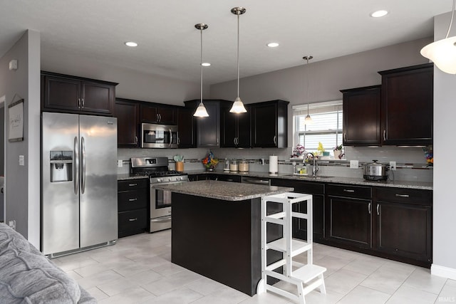 kitchen featuring sink, stainless steel appliances, decorative light fixtures, a kitchen bar, and a kitchen island