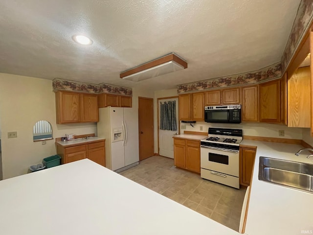 kitchen featuring a textured ceiling, sink, and white appliances