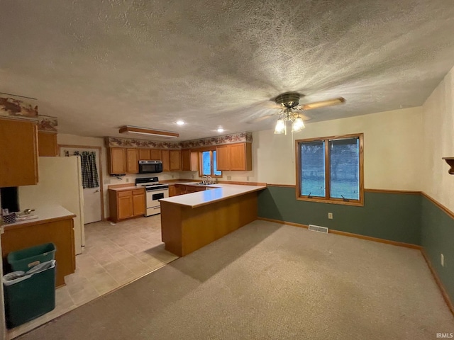 kitchen featuring a textured ceiling, kitchen peninsula, ceiling fan, and white appliances