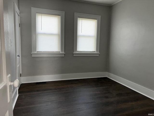 empty room featuring dark wood-type flooring and ornamental molding