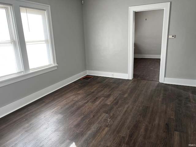 unfurnished room with dark hardwood / wood-style flooring and a healthy amount of sunlight