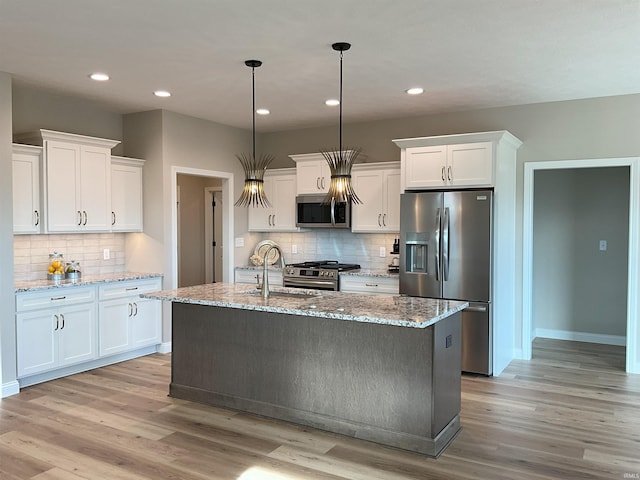 kitchen featuring appliances with stainless steel finishes, white cabinets, light stone counters, and decorative light fixtures