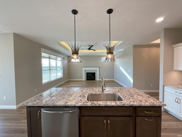 kitchen with white cabinetry, sink, light stone counters, and stainless steel dishwasher