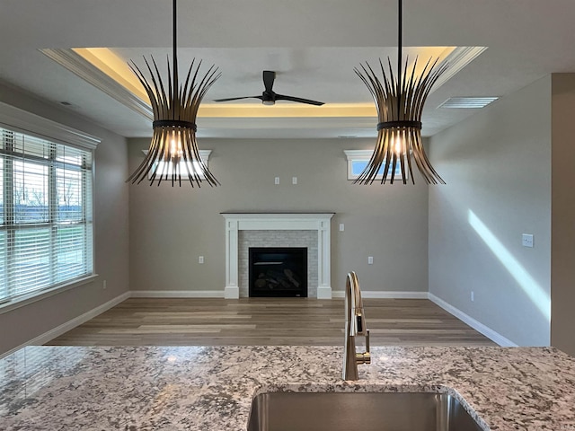 unfurnished living room featuring a fireplace, a raised ceiling, sink, and light hardwood / wood-style flooring