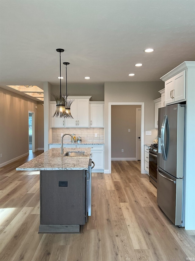 kitchen featuring sink, appliances with stainless steel finishes, pendant lighting, light stone countertops, and white cabinets