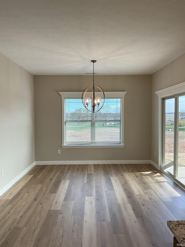 unfurnished dining area with a chandelier and light hardwood / wood-style floors