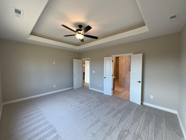 unfurnished bedroom with carpet, ceiling fan, and a tray ceiling