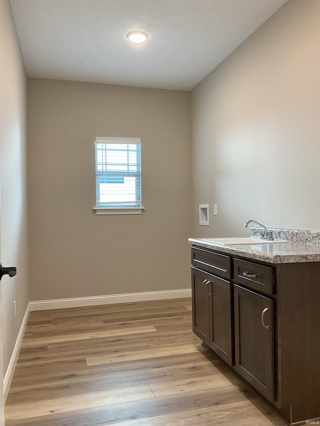 washroom with cabinets, sink, washer hookup, and light hardwood / wood-style flooring