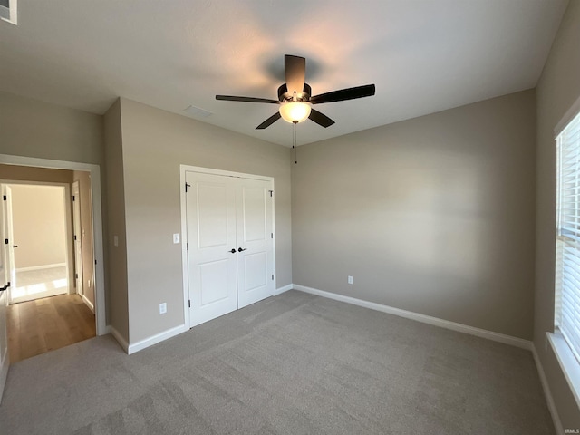 unfurnished bedroom featuring ceiling fan, carpet, and a closet