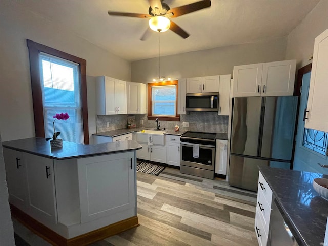 kitchen with light wood-type flooring, stainless steel appliances, white cabinetry, and backsplash