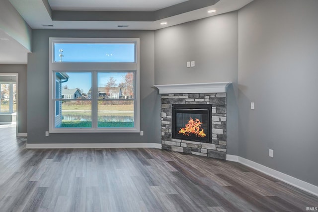 unfurnished living room featuring a stone fireplace and dark hardwood / wood-style floors