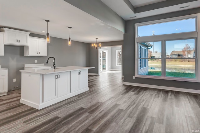 kitchen with white cabinetry, sink, an island with sink, a chandelier, and decorative light fixtures