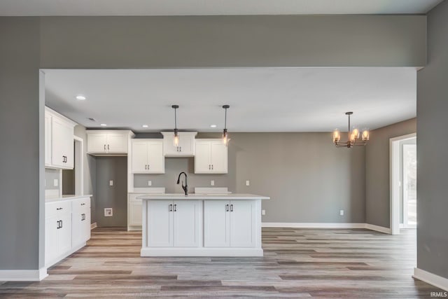 kitchen featuring a center island with sink, decorative light fixtures, light wood-type flooring, and a chandelier