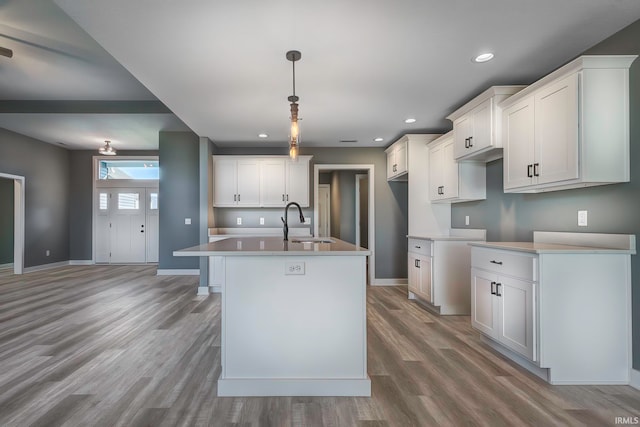 kitchen with white cabinetry, sink, pendant lighting, a center island with sink, and hardwood / wood-style flooring