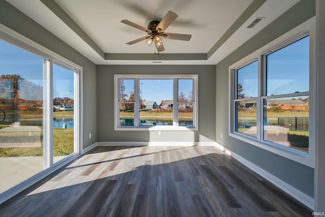 unfurnished sunroom with a water view, a raised ceiling, and ceiling fan