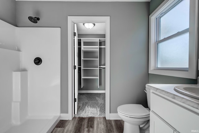 bathroom with hardwood / wood-style flooring, vanity, toilet, and walk in shower