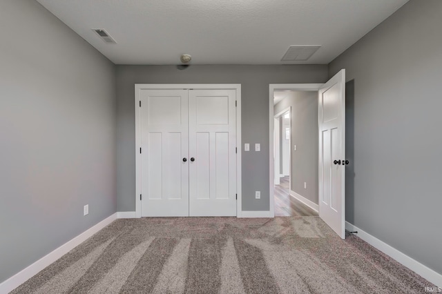 unfurnished bedroom with carpet flooring, a textured ceiling, and a closet