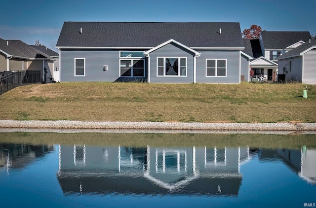 back of property featuring a water view and a lawn