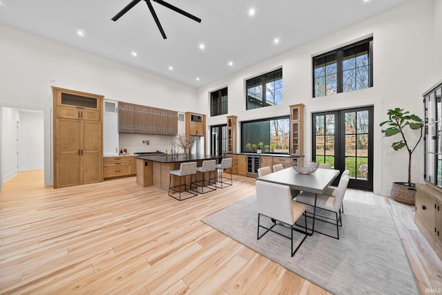 dining room featuring french doors, light hardwood / wood-style flooring, and a high ceiling