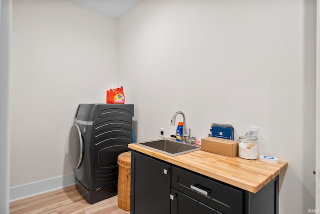 laundry room featuring washer / dryer, sink, cabinets, and light wood-type flooring