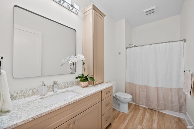 bathroom with toilet, vanity, and hardwood / wood-style flooring