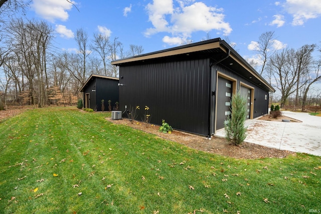 view of side of property featuring a lawn, central air condition unit, an outbuilding, and a garage