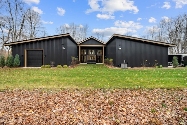 view of front of house with an outbuilding, a garage, cooling unit, and a front yard