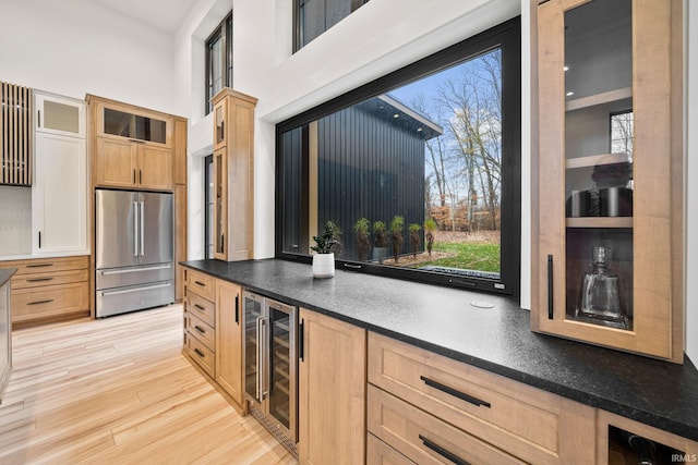 kitchen with high quality fridge, light hardwood / wood-style flooring, wine cooler, and light brown cabinets